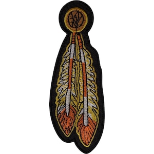 Puede incluir: Un parche bordado que presenta dos plumas colgando de un medallón circular. Las plumas están coloreadas en tonos naranja, amarillo y blanco, delineadas con hilo negro. La pieza circular superior es amarilla con detalles en negro.