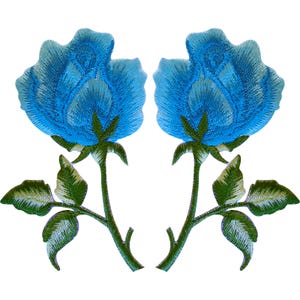 May include: Two identical embroidered patches featuring a blooming rose in shades of bright blue and light blue. Each rose has a green stem with three detailed green leaves attached. The embroidery shows visible thread texture and stitching patterns.