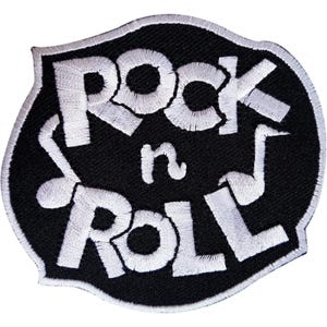 Pode incluir: Um emblema bordado preto com borda branca, apresentando o texto branco Rock n Roll e dois símbolos de notas musicais brancos em ambos os lados das letras. O emblema tem formato de escudo com bordas curvas e acabamento em tecido texturizado.