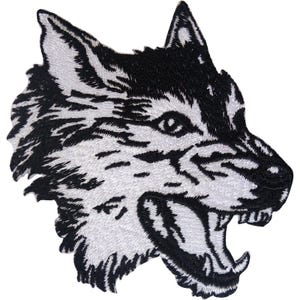 Peut inclure: Un écusson brodé représentant la tête d'un loup de profil, réalisé avec du fil noir et blanc à fort contraste. Le loup est représenté gueule ouverte, montrant les dents, avec une texture de fourrure détaillée créée par des points serrés.