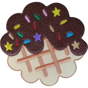 Op de afbeelding: Een geborduurde patch in de vorm van een wafelijzer met een bolletje donkerbruin ijs. Het ijs is versierd met kleurrijke hagelslag in rood, groen, blauw, geel, paars en roze, samen met kleine gele en beige stervormen.