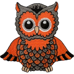 May include: An embroidered owl patch featuring a vibrant orange and dark gray color scheme. The owl has large, round black eyes with white highlights, a small tan beak, and detailed stitching that defines its feathers and wings.