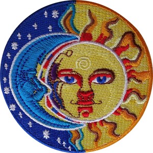 Op de afbeelding: Een ronde geborduurde patch met een verdeeld ontwerp van een blauwe halve maan aan de linkerkant met witte sterren en een gele zon aan de rechterkant. De zon heeft een gezicht met blauwe ogen en rode details, omringd door golvende stralen.