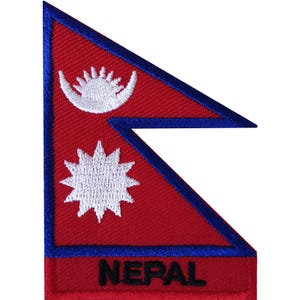 Peut inclure: Un écusson brodé représentant le drapeau du Népal avec un fond rouge, une bordure bleue et des symboles blancs en forme de soleil et de lune. Le mot NEPAL est brodé en lettres capitales noires au bas de l'écusson à la forme non rectangulaire.