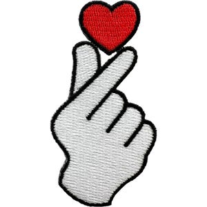May include: An embroidered patch featuring a white hand making a finger heart gesture with a red heart shape positioned above the thumb and index finger. The design is outlined in thick black thread, creating a bold and clear graphic representation.