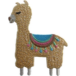 Könnte beinhalten: Ein gestickter Aufnäher in Form eines Lamas mit goldbraunem Garn, einer weißen Schnauze und geschlossenen Augen. Das Lama trägt eine Satteldecke mit konzentrischen Halbkreisen in Blau, Pink und Braun, verziert mit kleinen hängenden Quasten.