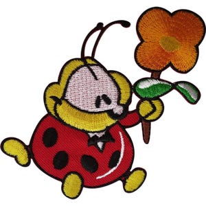 May include: An embroidered patch featuring a cartoon ladybug with a red body, black spots, and yellow limbs. The ladybug has a white face, yellow hair, and is holding a large orange flower with a green leaf and a brown stem in its hand.