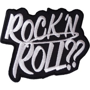 Pode incluir: Um emblema bordado com fundo preto e texto branco costurado que diz "ROCK'N ROLL??" em uma caligrafia cursiva estilizada. O emblema apresenta uma borda recortada que segue o contorno das letras, criando um contraste visual bem definido.
