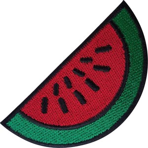May include: A semi-circular embroidered patch shaped like a watermelon slice. The design features a bright red center with scattered black embroidered seeds, surrounded by a green rind and a thick black stitched border outline.
