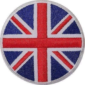 May include: A circular embroidered patch featuring the Union Jack flag design. The emblem displays a central red cross with white borders, set against a dark blue background, all enclosed within a stitched silver-grey circular border edge.