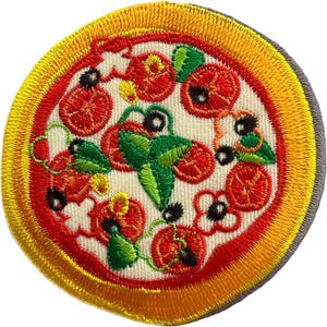 Könnte beinhalten: Ein kreisförmiger gestickter Aufnäher mit einem Pizzamotiv und einem dicken gelben Krustenrand. Die Mitte ist cremefarben mit roter Tomatensoße, grünen Basilikumblättern und verschiedenen kreisförmigen Belägen in Rot, Orange und Schwarz.