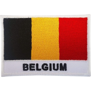 Pode incluir: Um emblema retangular bordado com a bandeira tricolor vertical da Bélgica, com faixas preta, amarela e vermelha. Uma faixa horizontal branca na parte inferior contém a palavra BELGIUM bordada em letras maiúsculas azul-escuras.