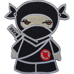 May include: An embroidered patch featuring a cartoon ninja character in a black outfit with silver-grey trim. The ninja has a mask covering the lower face, visible eyes with long lashes, a sword strapped to the back, and a red circular emblem on the chest.