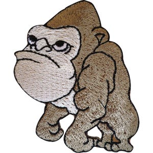 May include: An embroidered patch featuring a cartoon gorilla with light brown fur and a cream-coloured face. The gorilla is depicted in a hunched, walking posture with a stern facial expression, defined by thick black outlines and detailed stitching.