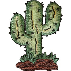 May include: An embroidered patch featuring a green saguaro cactus with yellow highlights and dark green spines. The cactus is rooted in a patch of brown soil with small green sprouts at the base. The design is outlined in black thread.