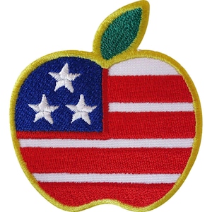 May include: An embroidered patch in the shape of an apple. The left side features a blue field with three white stars, while the right side displays horizontal red and white stripes. The apple has a green leaf at the top and a yellow border.