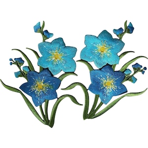 Puede incluir: Dos parches bordados que presentan flores de color azul vibrante con centros amarillos y tallos verdes. Cada parche muestra un grupo de flores y capullos con costuras detalladas, exhibiendo una paleta de colores azul brillante y follaje verde.