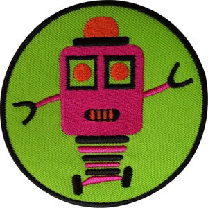 Puede incluir: Un parche bordado circular con un fondo verde lima brillante y un borde negro. En el centro hay un robot rosa con una parte superior roja, ojos circulares naranjas y una boca negra con dientes naranjas. El robot tiene brazos rosas y manos negras.