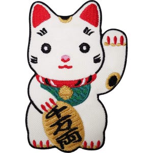 Puede incluir: Un parche bordado de un gato de la suerte blanco con orejas rojas, ojos y bigotes negros. El gato lleva un collar rojo con un babero verde y un cascabel dorado. Sostiene una moneda ovalada dorada con caracteres kanji japoneses en color negro.