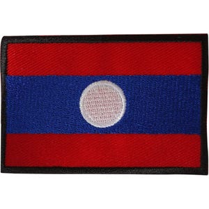 Op de afbeelding: Een rechthoekige geborduurde patch met de vlag van Laos. Het ontwerp bestaat uit een brede blauwe horizontale band in het midden met een witte cirkel, geflankeerd door twee rode horizontale banden van gelijke breedte, afgezet met een zwarte rand.