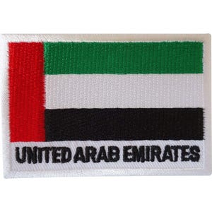 May include: A rectangular embroidered patch featuring the flag of the United Arab Emirates with a vertical red stripe on the left and horizontal green, white, and black stripes on the right. The text UNITED ARAB EMIRATES is stitched in black.