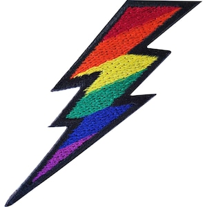 Può includere: Una toppa ricamata a forma di fulmine. Il design presenta strisce orizzontali di filo rosso, arancione, giallo, verde, blu e viola, il tutto delineato da un bordo nero spesso su uno sfondo nero a tinta unita.