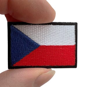 Può includere: Una toppa rettangolare ricamata che raffigura la bandiera della Repubblica Ceca. Il design è composto da un triangolo blu sul lato sinistro, con una striscia orizzontale bianca in alto a destra e una striscia orizzontale rossa in basso.