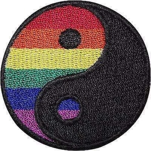 May include: A circular embroidered patch featuring a yin and yang symbol. One half of the circle is filled with horizontal stripes in red, orange, yellow, green, blue, and purple, while the other half is solid black with a small rainbow-coloured dot.