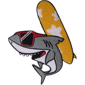 May include: An embroidered patch featuring a grey shark wearing red-framed sunglasses, positioned in front of a yellow surfboard with white flower patterns. The shark has a white underbelly, visible teeth, and a black mouth, with a grey tail fin.