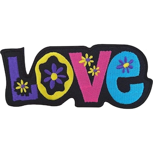 Puede incluir: Un parche bordado con la palabra LOVE en una fuente estilizada y llamativa. La letra L es morada con una flor amarilla, la O es amarilla con una flor morada, la V es rosa con dos flores amarillas y la E es azul con una flor morada sobre negro.