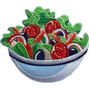Peut inclure: Un écusson brodé représentant une salade dans un bol bleu clair. Le motif présente des feuilles de laitue vert vif, des tranches de tomates rouge éclatant et des olives bleu foncé, le tout réalisé avec des points détaillés sur une base en tissu.