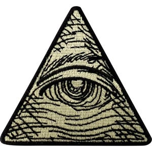 May include: A triangular embroidered patch featuring an all-seeing eye design. The patch is rendered in off-white and black thread, depicting a detailed eye centered within a pyramid shape, finished with a thick black stitched border edge.