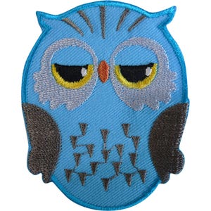 May include: An embroidered owl patch featuring a light blue body with dark gray wings. The owl has large eyes with yellow irises, white feathered patches around the eyes, a small orange beak, and dark gray triangular markings on its chest.