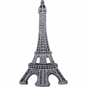 Op de afbeelding: Een geborduurde patch in de vorm van de Eiffeltoren. Het ontwerp heeft een zwarte achtergrond met gedetailleerde zilverkleurige stiksels die het rasterachtige structuurframe van de toren vanaf de basis tot aan de puntige top omlijnen.