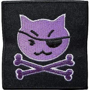 May include: A square black embroidered patch featuring a purple cat head with a black eye patch over one eye and a pair of purple crossed bones positioned directly underneath the cat head, all rendered in a stitched thread design.