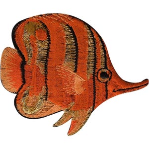 May include: An embroidered patch shaped like a tropical fish. The fish is primarily orange with vertical black stripes and gold-coloured thread accents throughout the body, fins, and tail. It features a pointed snout and a small, circular black eye.