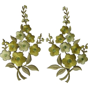 Puede incluir: Dos parches bordados a juego con un arreglo floral en tonos verde oliva, lima y chartreuse. Cada parche muestra un tallo central con varias flores de cinco pétalos, pequeños capullos y hojas puntiagudas, todo realizado en hilo bordado.