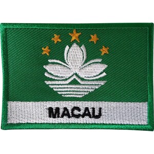 May include: A rectangular embroidered patch featuring a green background with a white lotus flower emblem above a white horizontal stripe. Five gold stars are arranged in an arc above the lotus. The word MACAU is stitched in black on the white stripe.
