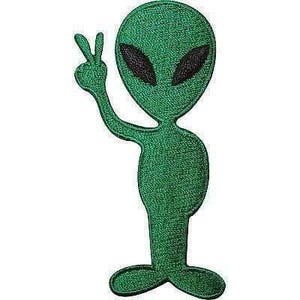 Può includere: Una toppa ricamata raffigurante una figura aliena verde con una grande testa ovale e occhi neri a mandorla. L'alieno è raffigurato in posizione eretta con un braccio sollevato, facendo un segno di pace con le dita.
