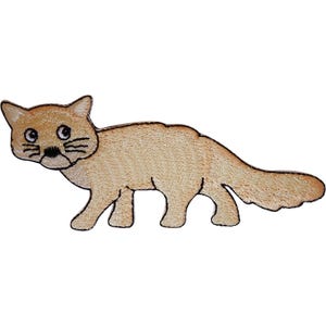 Op de afbeelding: Een geborduurde patch met een tan-kleurige wilde kat met een lange staart, puntige oren en zwarte gestikte details voor de ogen, neus en snorharen. Het dier is afgebeeld in zijaanzicht, staand op vier poten met een lichtgekleurde buik.