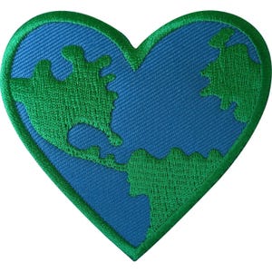 May include: A heart-shaped embroidered patch featuring a blue background with green landmass shapes. The patch has a thick, stitched green border that outlines the heart shape, creating a distinct contrast between the blue and green colors.