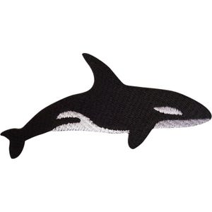 Op de afbeelding: Een geborduurde patch in de vorm van een orka. Het ontwerp heeft een zwart lichaam met een prominente rugvin, een witte oogvlek en een wit buikgedeelte, allemaal uitgevoerd met gedetailleerd stikwerk tegen een effen achtergrond.