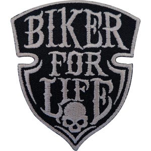May include: A shield-shaped embroidered patch with a black background and white border. The text BIKER FOR LIFE is stitched in a bold, stylized white font across the center, with a small white skull icon positioned below the lettering.