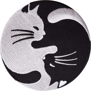 以下が含まれることがあります： 白と黒の2匹の猫が陰陽の形に配置された、円形の刺繍ワッペン。左側に白い猫、右側に黒い猫が配置されており、それぞれの体が曲線を描いて円形を形成しているデザインです。