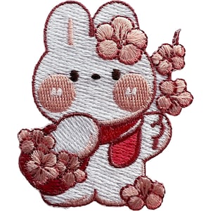 Pode incluir: Um emblema bordado apresentando um coelho branco com bochechas rosadas, usando um cachecol vermelho e cercado por cachos de flores de cerejeira cor-de-rosa. O design é contornado com fio vermelho escuro, criando uma aparência detalhada e texturizada.