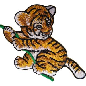 Può includere: Una toppa ricamata raffigurante un cucciolo di tigre con pelliccia arancione, nera e bianca. Il cucciolo è raffigurato in posizione seduta, mentre tiene un sottile stelo verde con le zampe anteriori. Il design presenta cuciture dettagliate e un bordo nero.