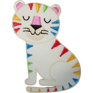 Peut inclure: Un écusson thermocollant brodé en forme de tigre assis, avec un tissu blanc et des rayures colorées en rouge, jaune, vert et bleu. Le tigre a un nez et des oreilles roses, des yeux fermés et une bouche noire brodée, le tout bordé de fil blanc.