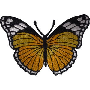 Op de afbeelding: Een geborduurde vlinderpatch met een levendig oranje en geel vleugelpatroon met zwarte randen en witte accenten. Het ontwerp bevat een effen zwart centraal lichaam en twee zwarte voelsprieten, met gedetailleerd borduurwerk over het geheel.