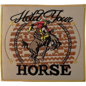 Op de afbeelding: Een vierkante geborduurde patch met een beige achtergrond en een bruin geometrisch patroon. De tekst Hold Your HORSE is in het zwart geborduurd. Een centrale afbeelding toont een cowboy in een rood hemd en gele broek op een bokkend bruin paard.