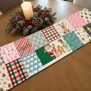 May include: A quilted Christmas table runner featuring a patchwork design of holiday patterns including Santa Claus, reindeer, candy canes, gingerbread cookies, and a nativity scene with the text Merry Christmas on a red and white striped square.